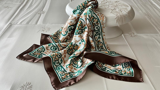 Hand-hemmed lightweight silk scarf with intricate green and brown floral patterns and a dark brown border on white background