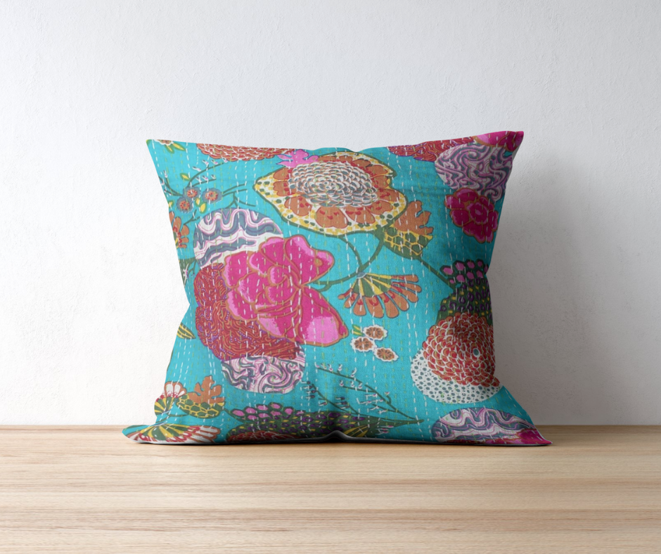 Colorful hand-stitched Kantha throw pillow with floral pattern on a wooden surface