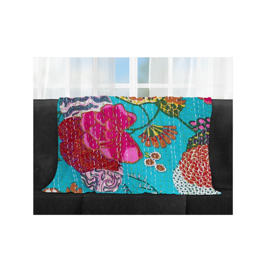 Bright tropical kantha blanket with hand-stitched floral patterns in vibrant blue and pink on sofa.
