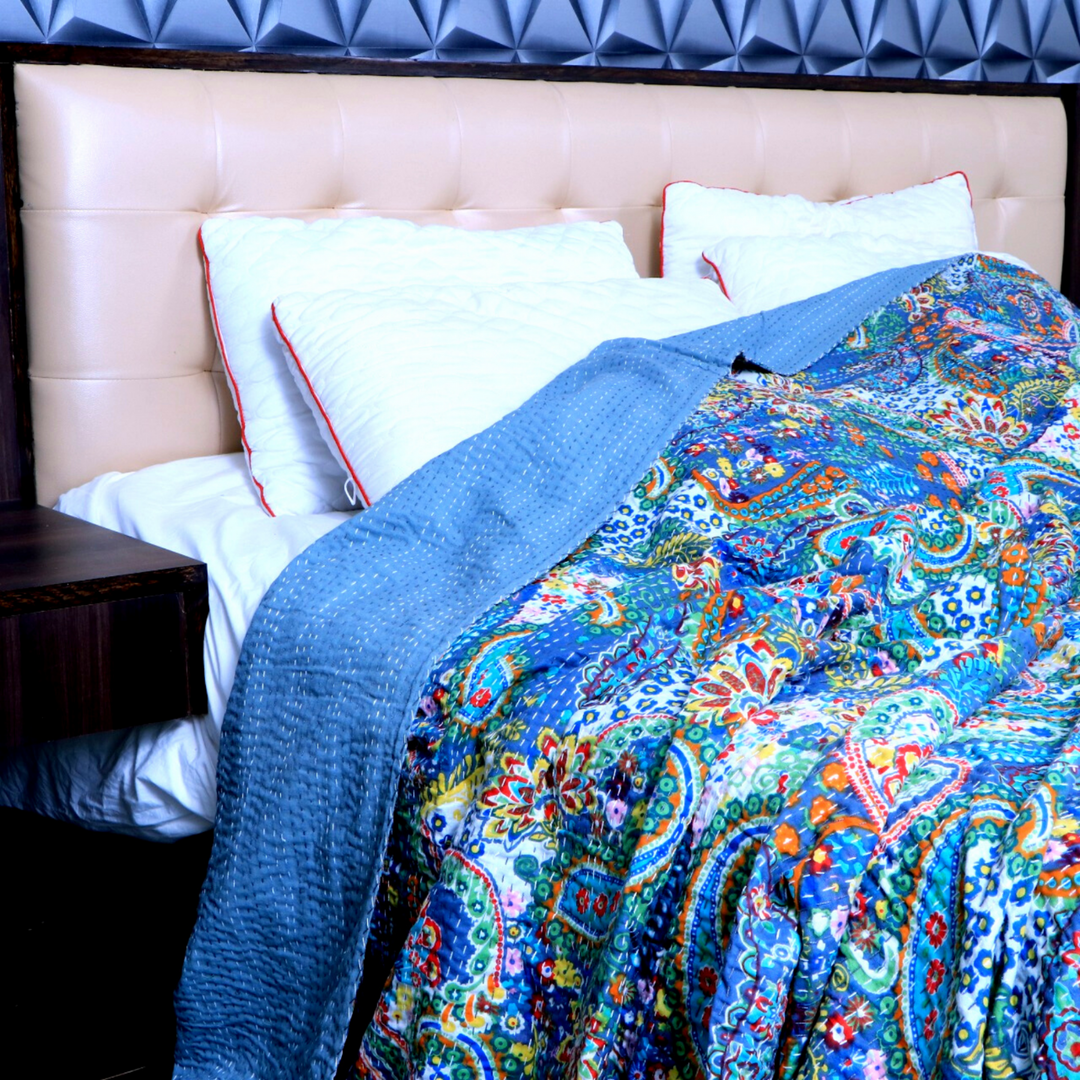 Kantha blanket set with colorful paisley hand-stitched quilt and pillowcases on bed with tufted headboard