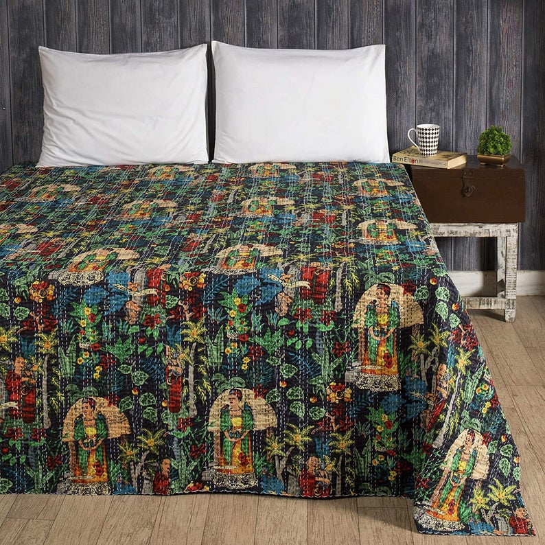 Hand-stitched colorful Kantha blanket featuring Frida Kahlo inspired floral and pattern design on a bed with wooden backdrop