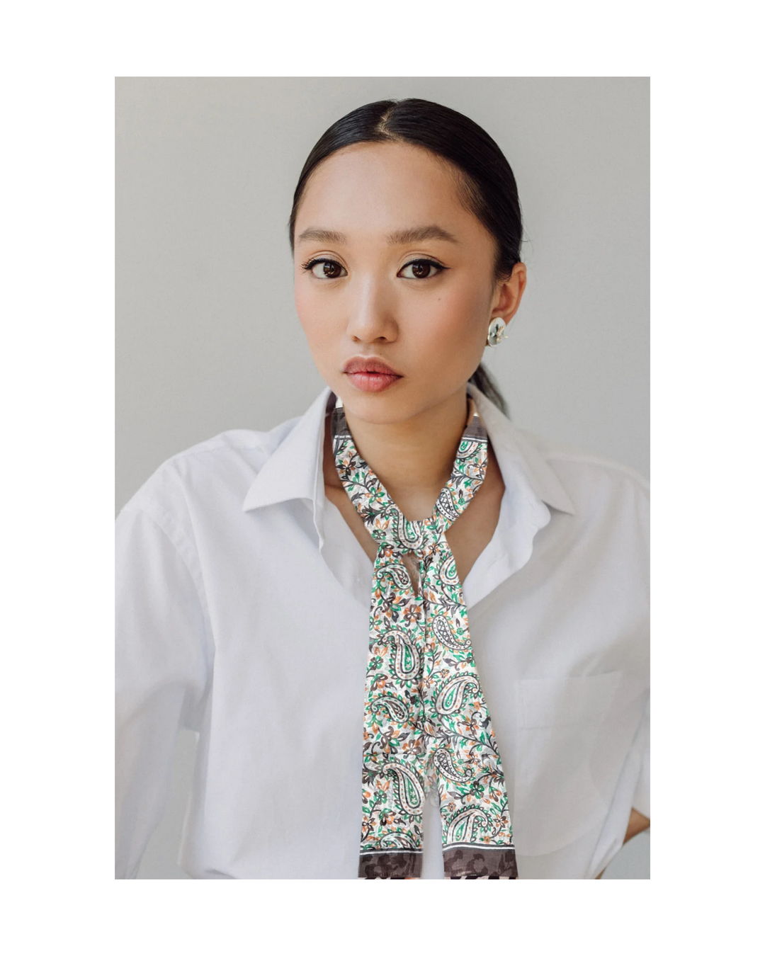 luxurious hand-hemmed silk scarf in bright colors worn by a model with a white blouse